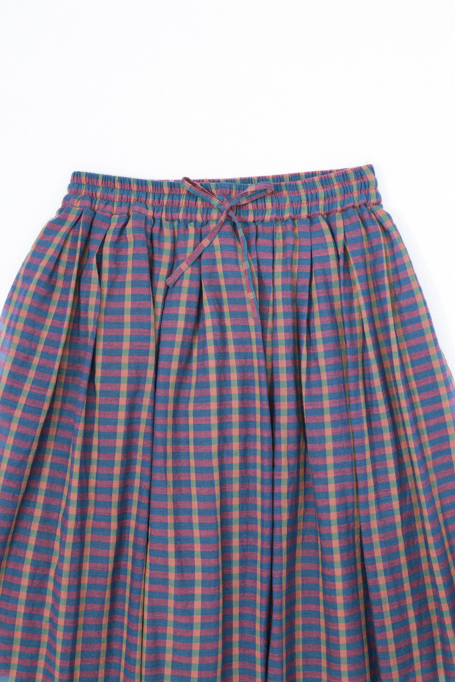Plains Design - Twin Skirt in Purple. Close up of waist and front of purple and blue striped plaid skirt with pockets and a tie waist. Handspun cotton fabric.