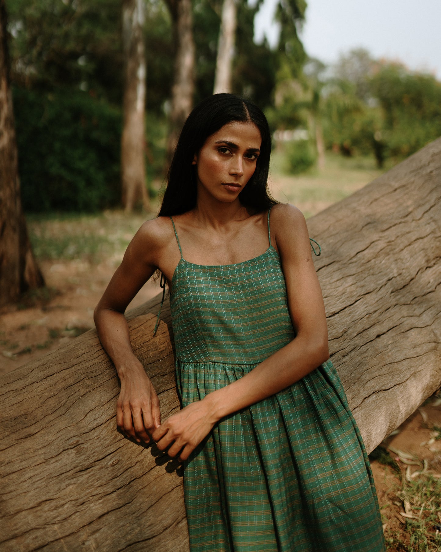 Plains Design - River mulberry silk cotton dress. Sleeveless midi dress with spaghetti straps, and a gathered waist in a green cotton mulberry silk fabric with red and white checks. Ethically handmade and handspun in India.