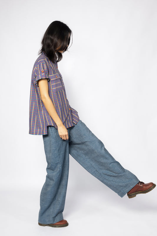 Plains Design Billie Denim Pants – handwoven cotton denim wide-leg pants in mid blue, oversized fit, styled with a short-sleeved stripe shirt