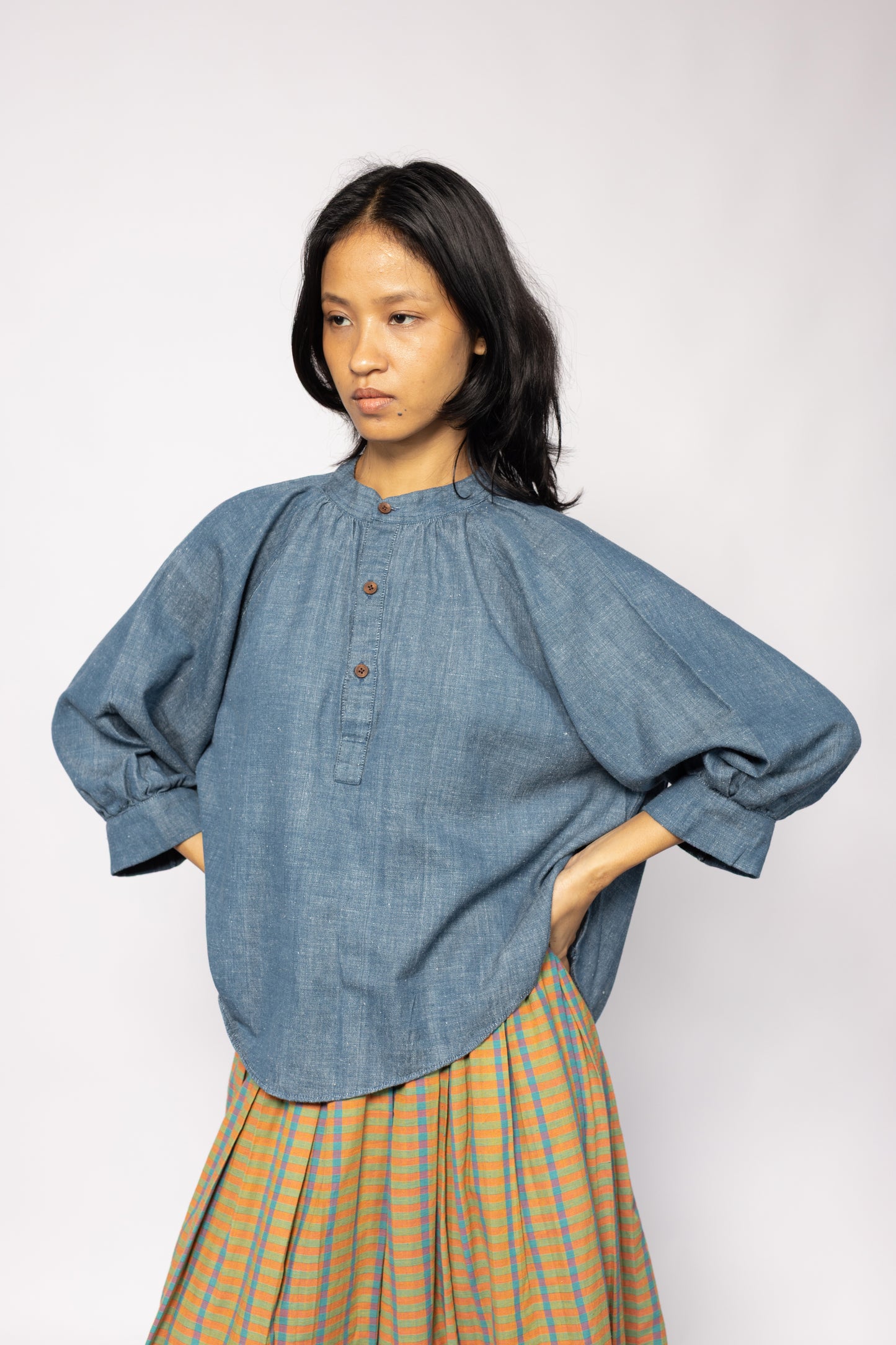 Plains Design - Sault wide sleeved top. Blue denim wide sleeved top with wooden buttons and side slits in a relaxed fit. Paired with an orange skirt. Ethically handmade in India with handspun cotton twill denim.