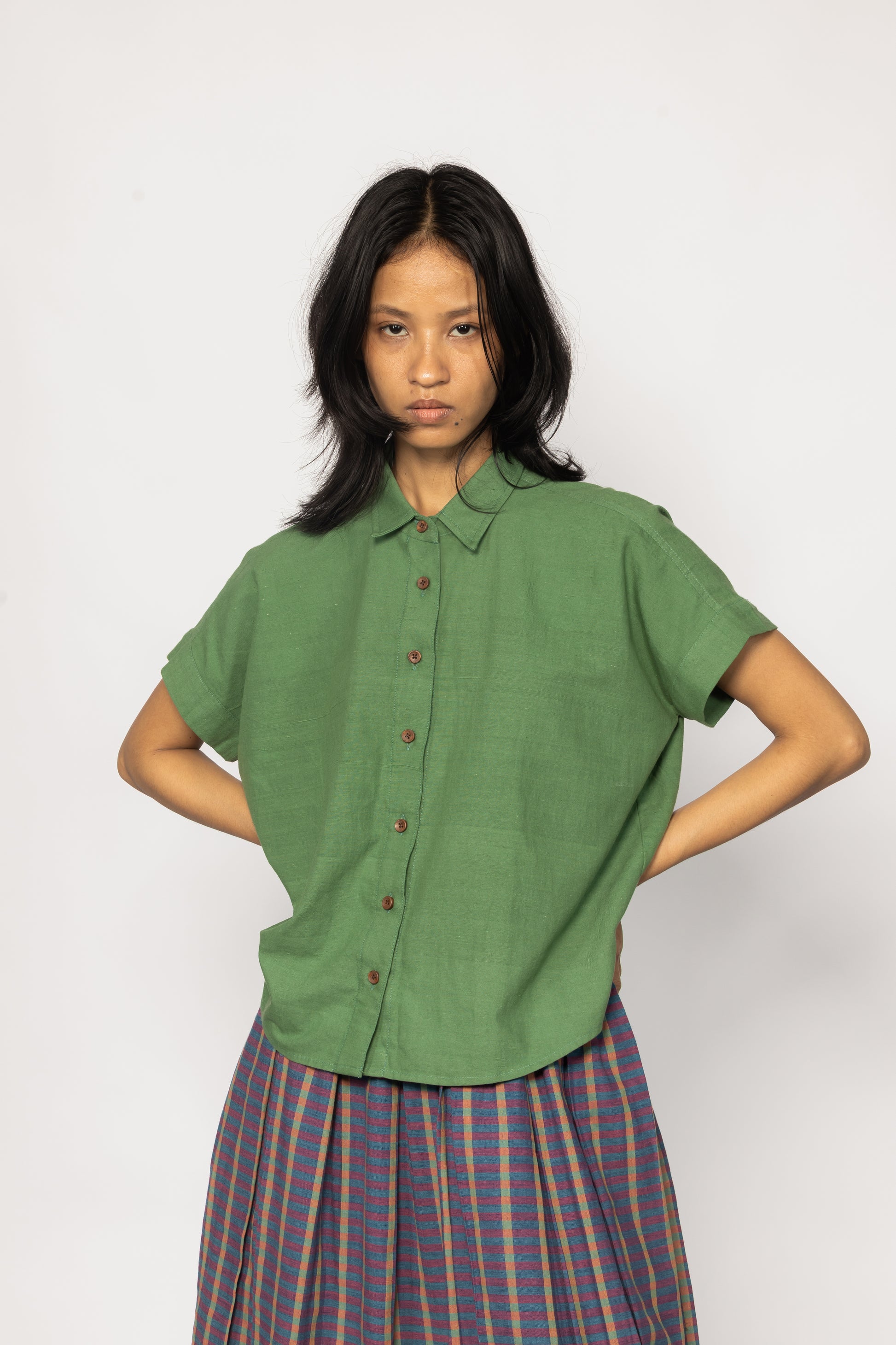 Plains Design - Bud Shirt. Bright green short sleeved shirt with wooden buttons paired with a skirt. Handwoven cotton. Sustainable fashion