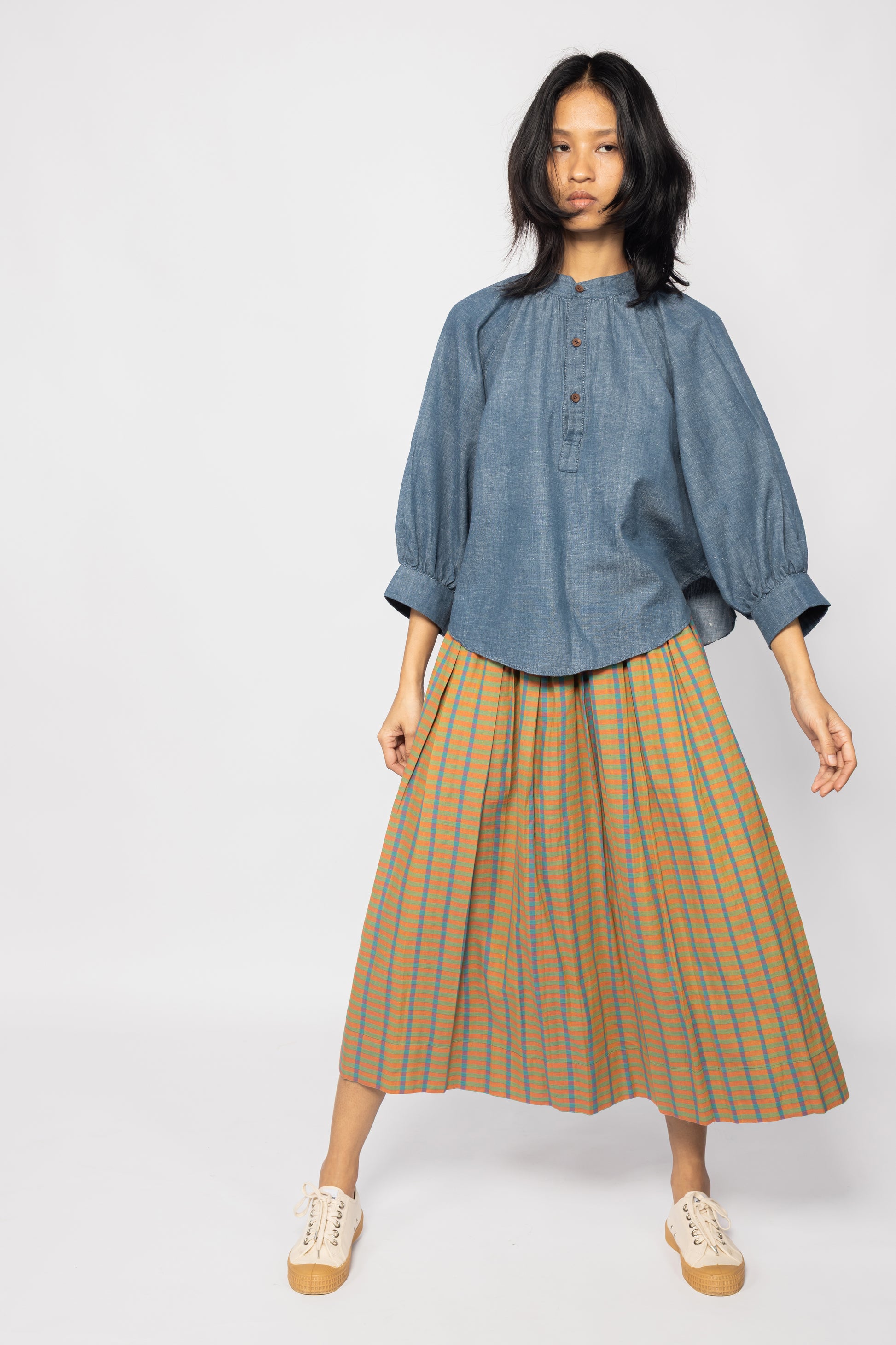 Plains Design - Twin skirt in Orange. Midi skirt with orange, blue and yellow checks in a relaxed fit. Paired with a denim top and canvas shoes. Ethically handmade with handspun cotton in India.