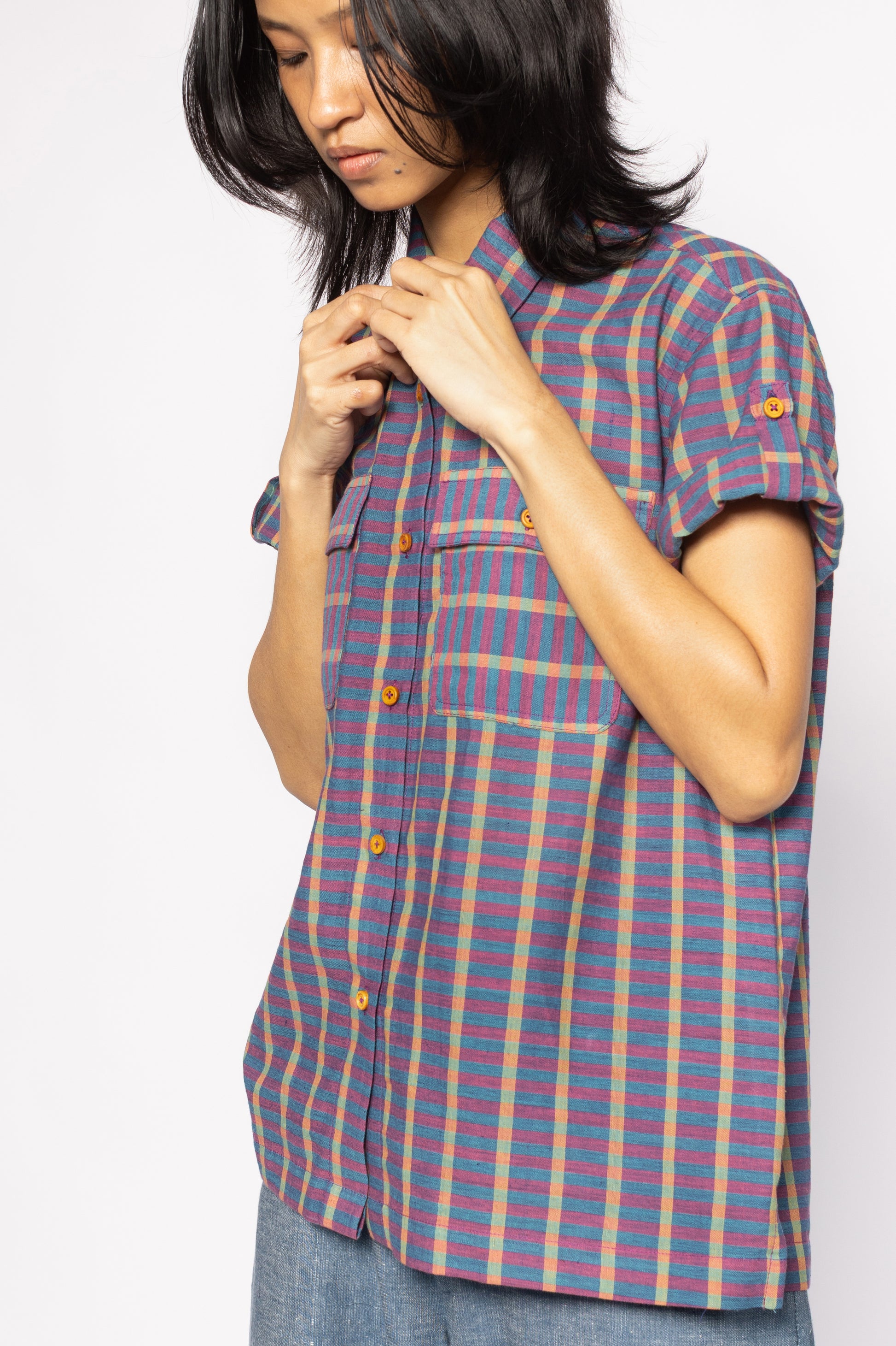 Plains Design - Twin Shirt in Purple. Purple striped button up shirt with pockets on chest and wooden buttons. Short foldable sleeves with buttons. Paired with blue denim pants.